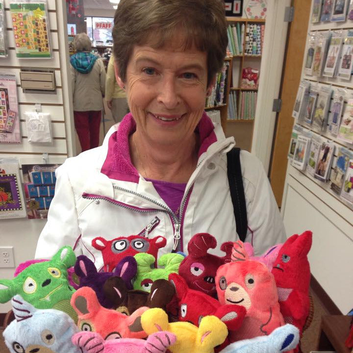 Woman holding a basket of colorful plush toys in a store setting