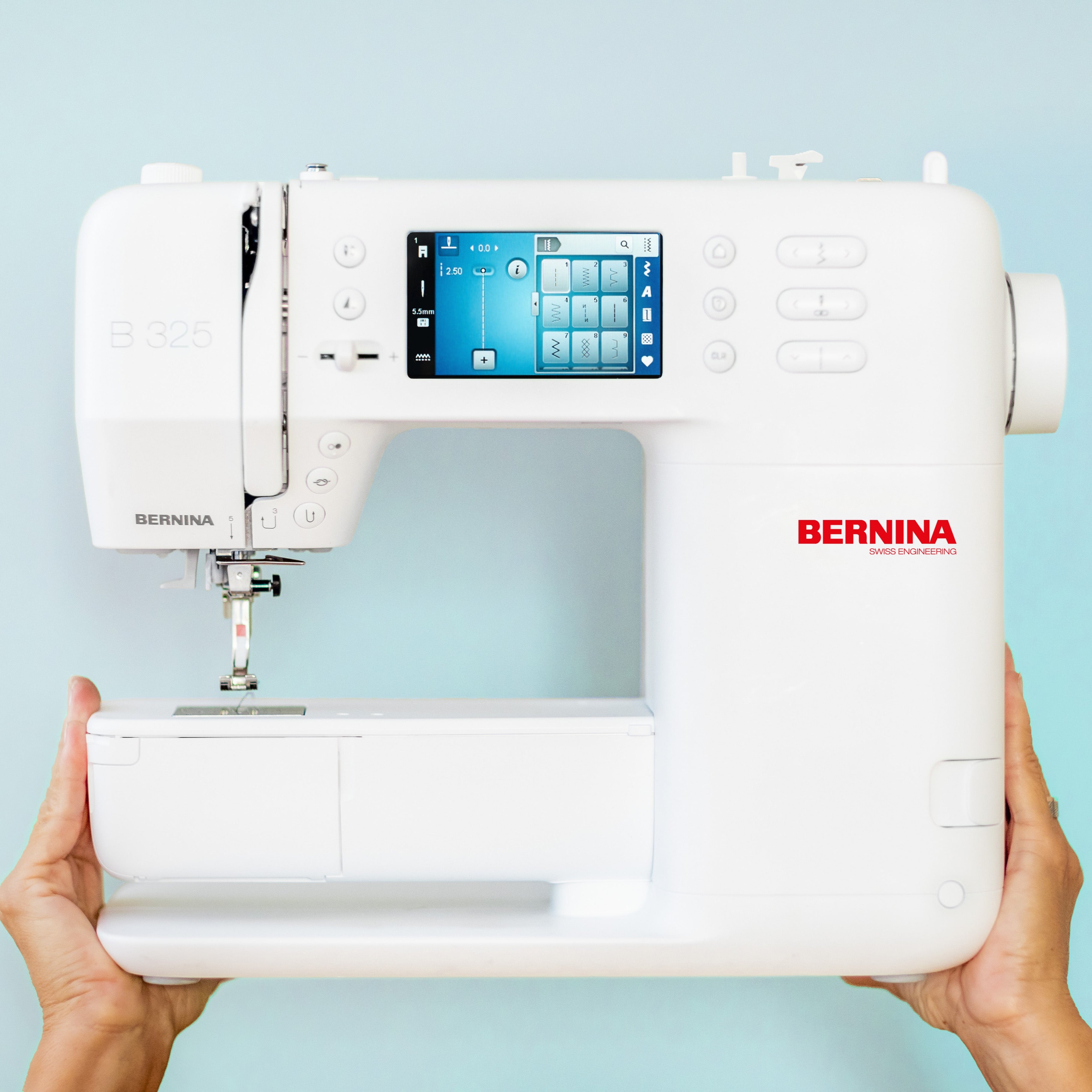 Bernina sewing machine held by hands against a light blue background