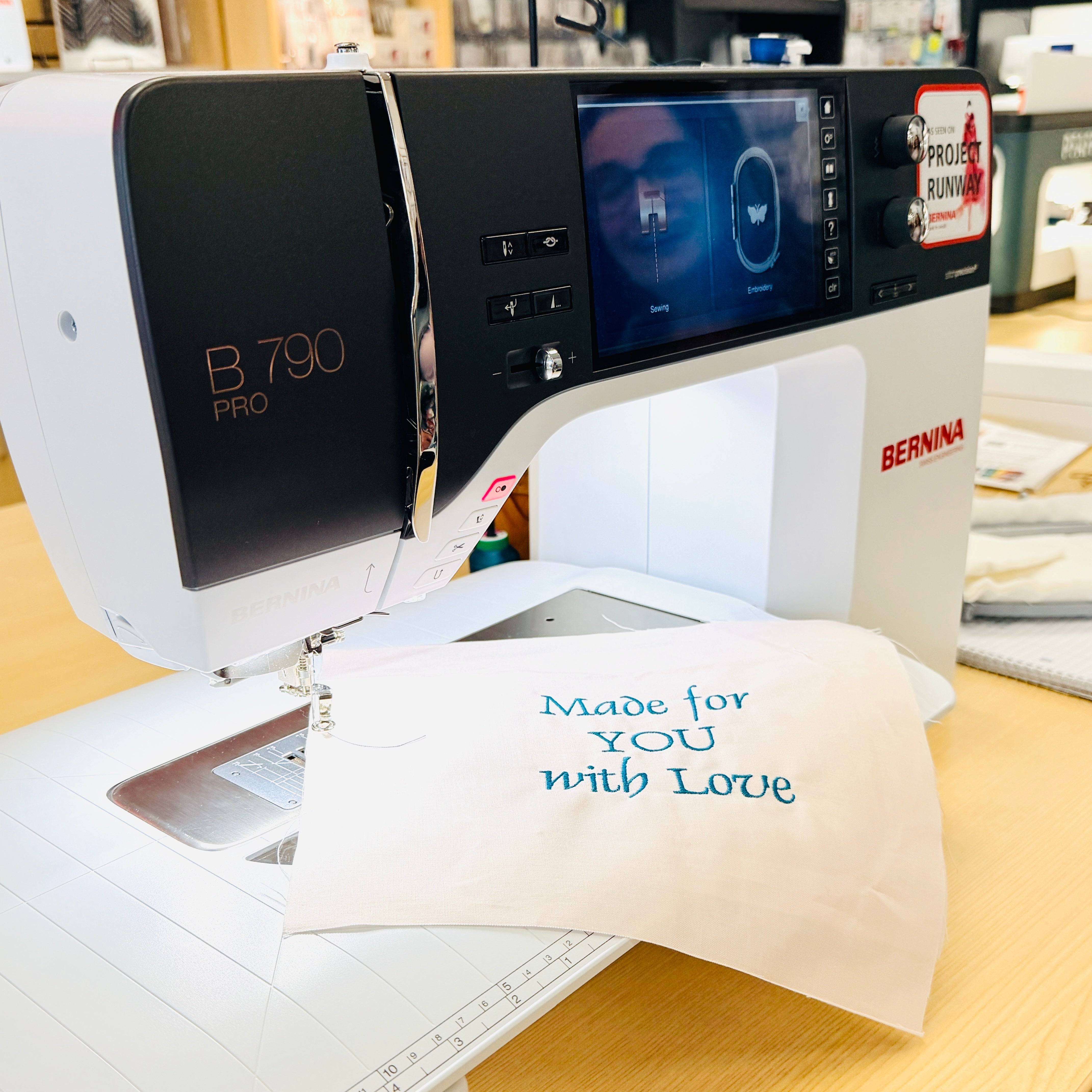 Sewing machine with a piece of fabric that reads 'Made for YOU with Love' on a wooden table.