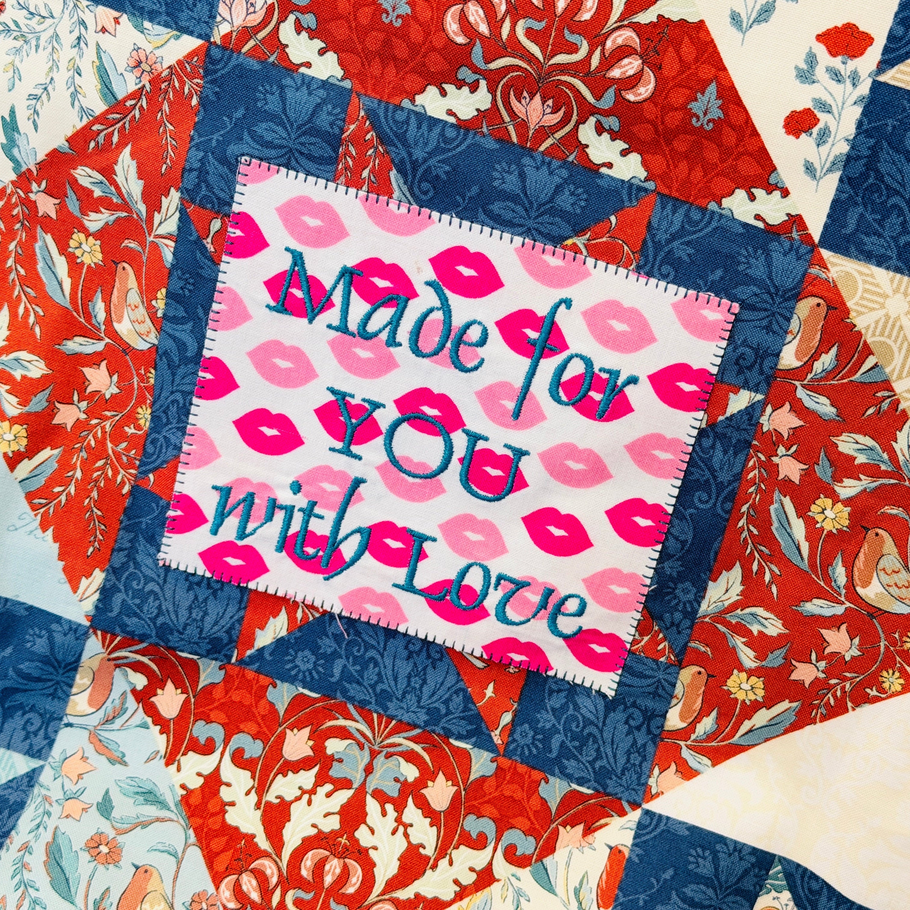 Quilt with a patchwork design featuring a pink label with 'Made for YOU with Love' text.