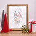 Framed Christmas ornament design with decorative items on a table.