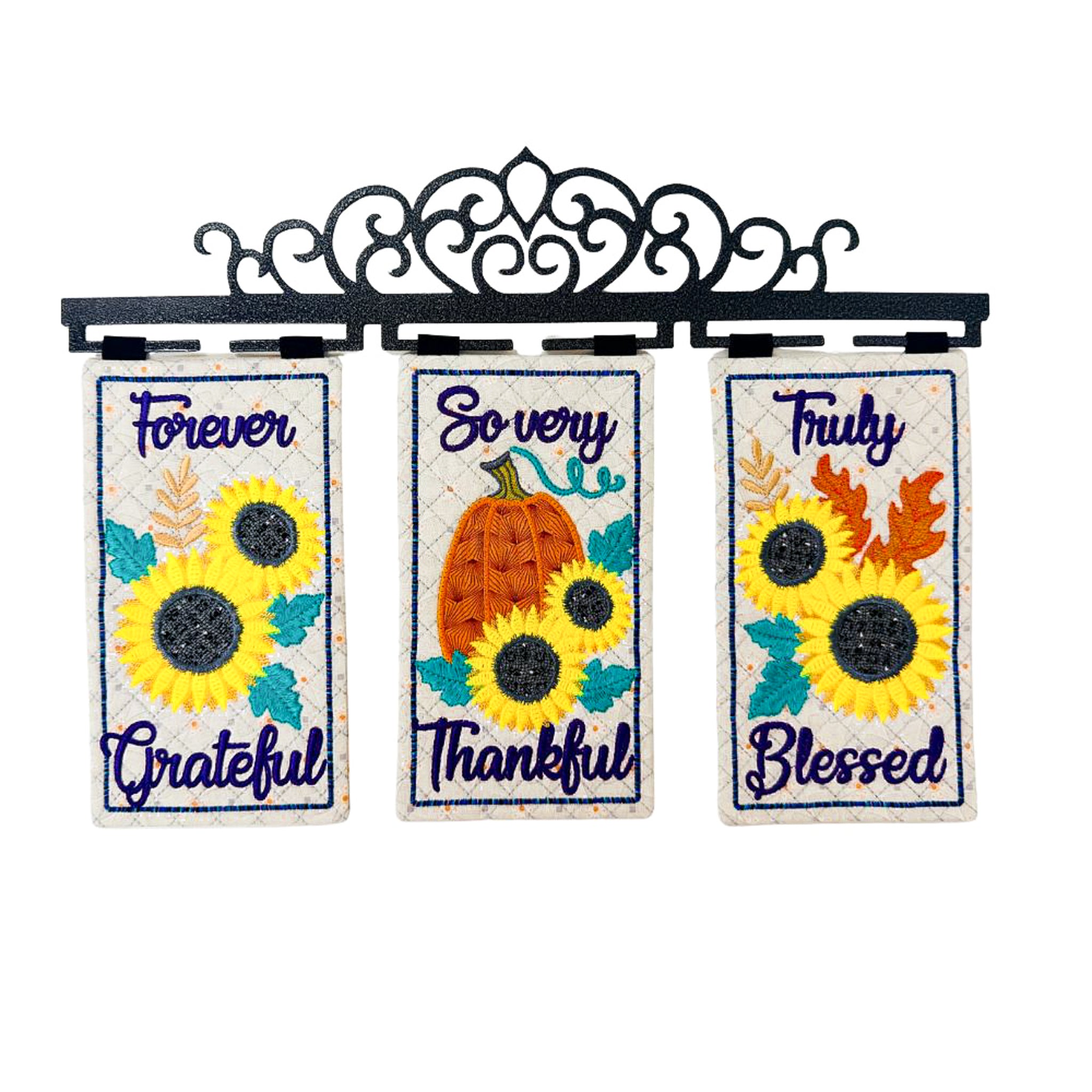 Three vertical decorative garden flags hanging from a black metal scrollwork bracket. The flags feature autumn-themed designs: the left says 'Forever Grateful' with yellow sunflowers, the center says 'So very Thankful' with a pumpkin and sunflowers, and the right says 'Truly Blessed' with sunflowers and autumn leaves.