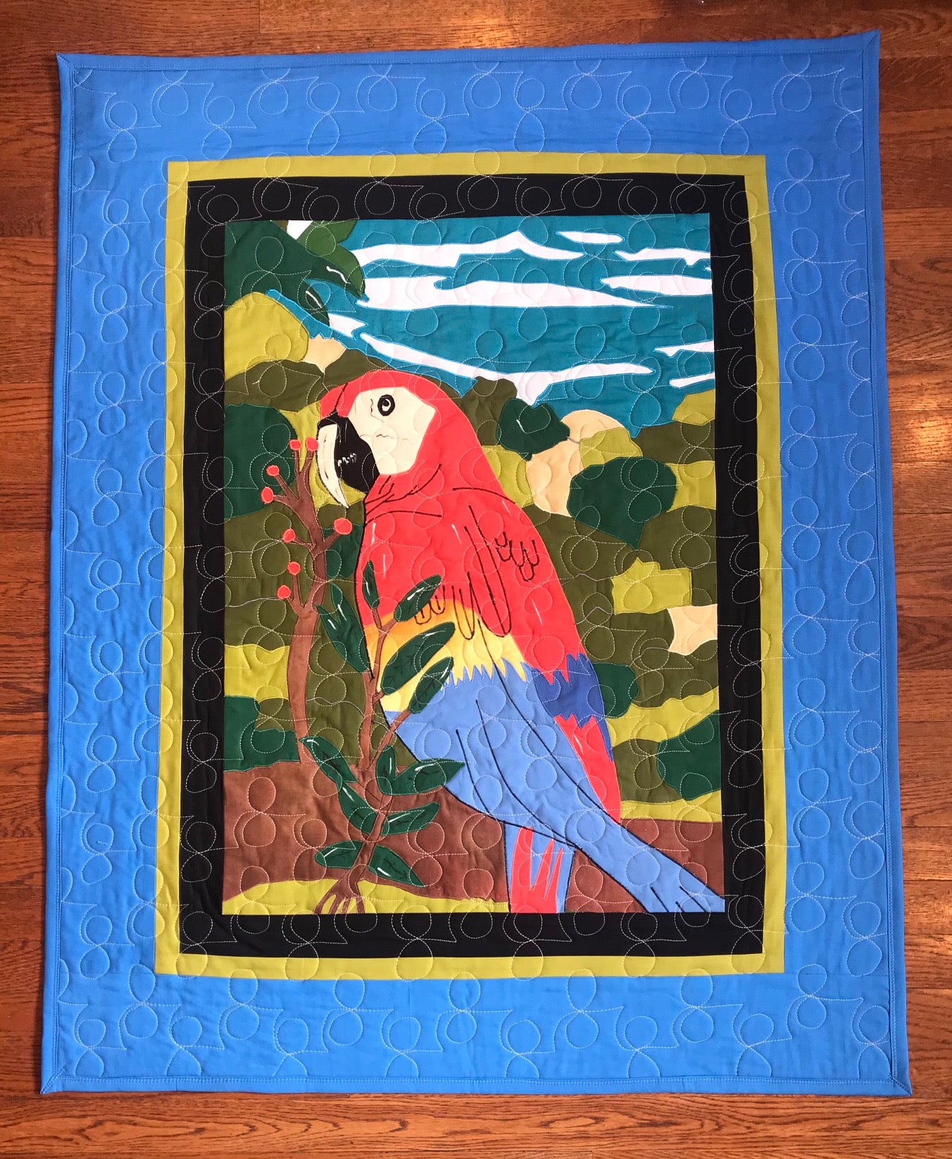 Quilt with a colorful parrot design on a blue background