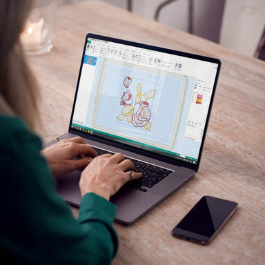 Person using a laptop with a design on the screen at a wooden table.