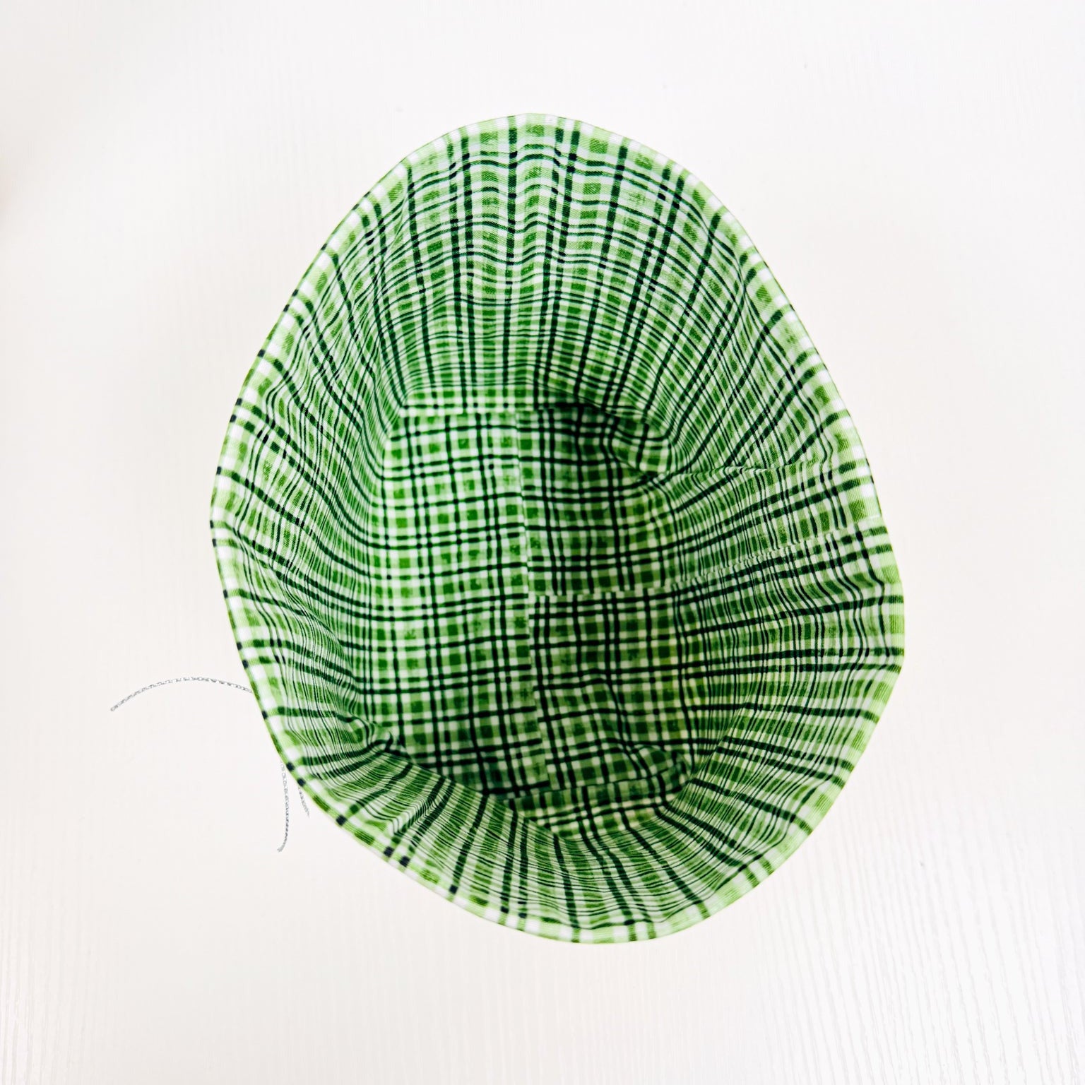 A fabric-covered chair insert or small chair with a green and black plaid pattern, photographed from above on a white background.