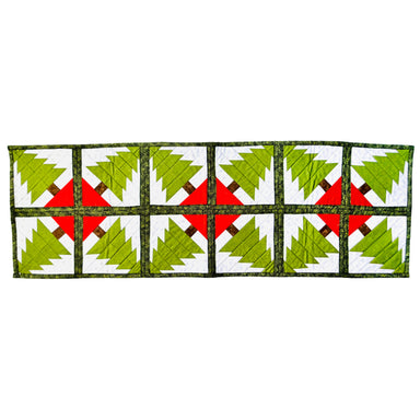 A rectangular quilted table runner featuring a repeating pattern of green Christmas trees on white panels, separated by red X-shaped centers and dark green borders.