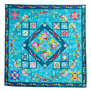 Colorful quilt with floral and geometric patterns on a blue background