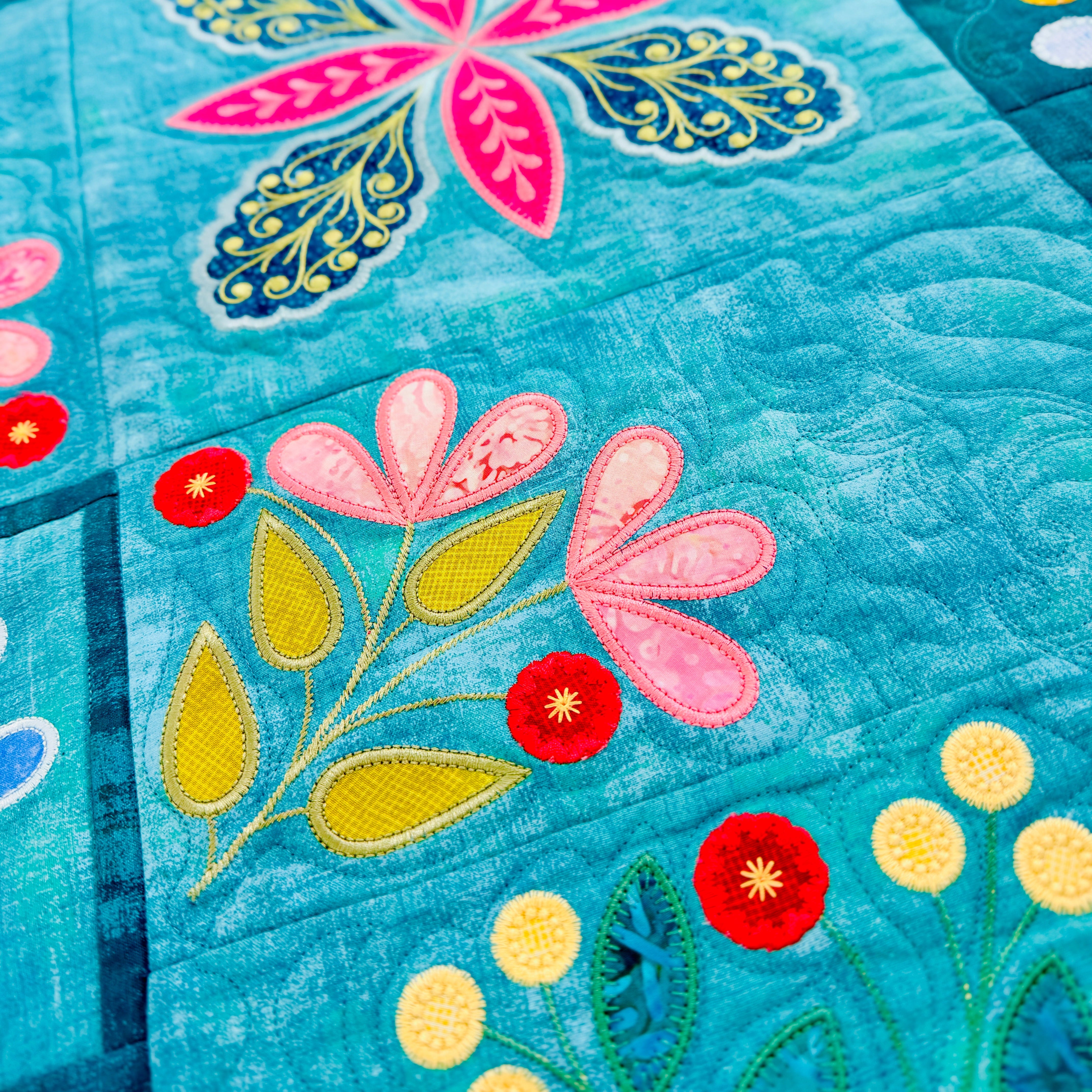 Colorful floral and butterfly design on a quilt with a blue background