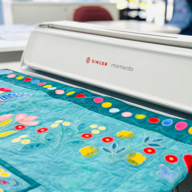 Singer sewing machine with a floral quilt on a table