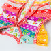 A colorful patchwork apron with a red and white gingham border and tie, featuring various floral and patterned fabric panels in pink, purple, blue, yellow, and red, laid flat on a white background.