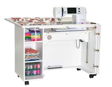 Sewing machine on a white table with storage shelves and colorful thread spools.