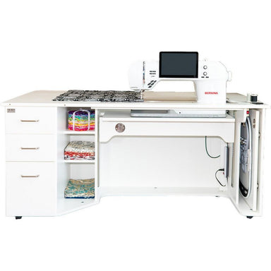 Sewing machine on a white desk with storage compartments.