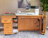 Wooden sewing desk with a Bernina sewing machine in a home setting.