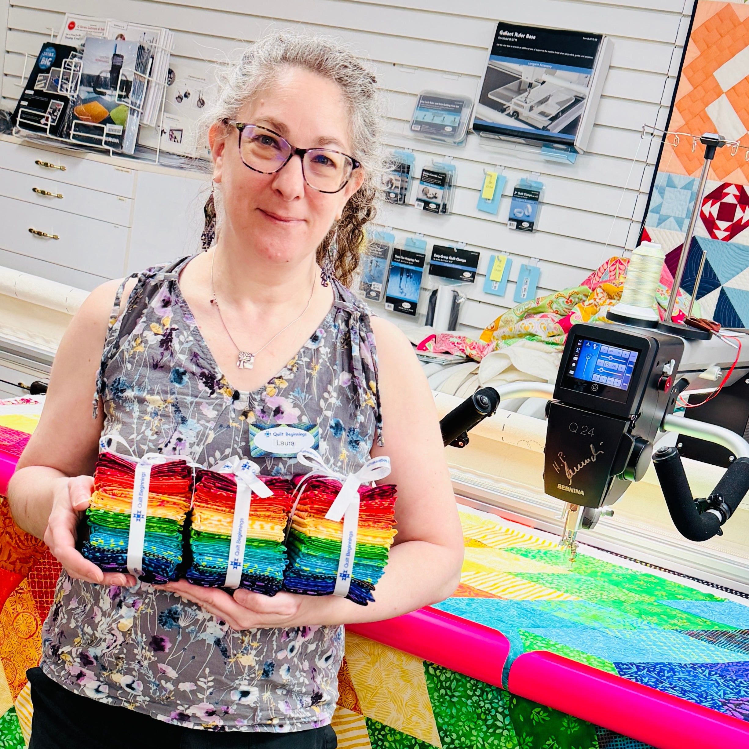 Person holding a colorful quilted item in a store setting with sewing equipment.