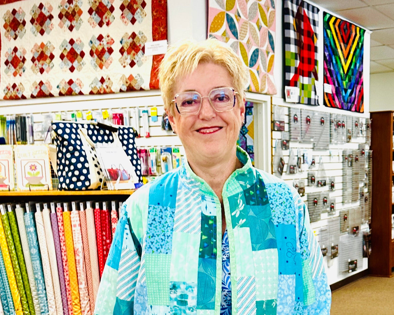 Person wearing a colorful quilted jacket in a fabric store