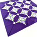 Purple quilt block with floral pattern on a white background