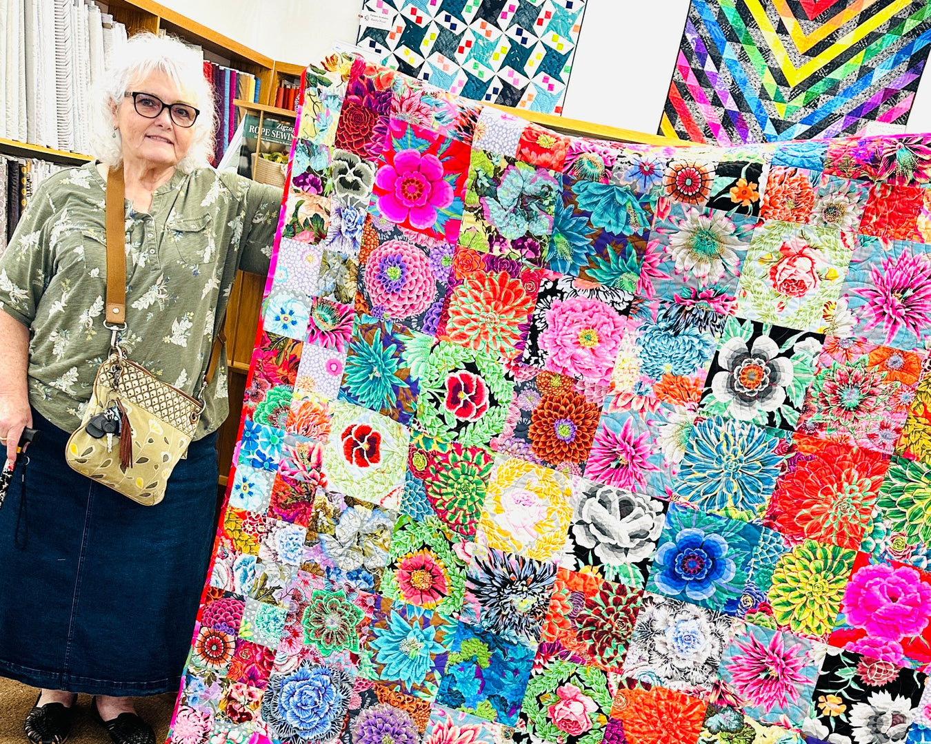 Woman standing next to a colorful quilt with floral patterns