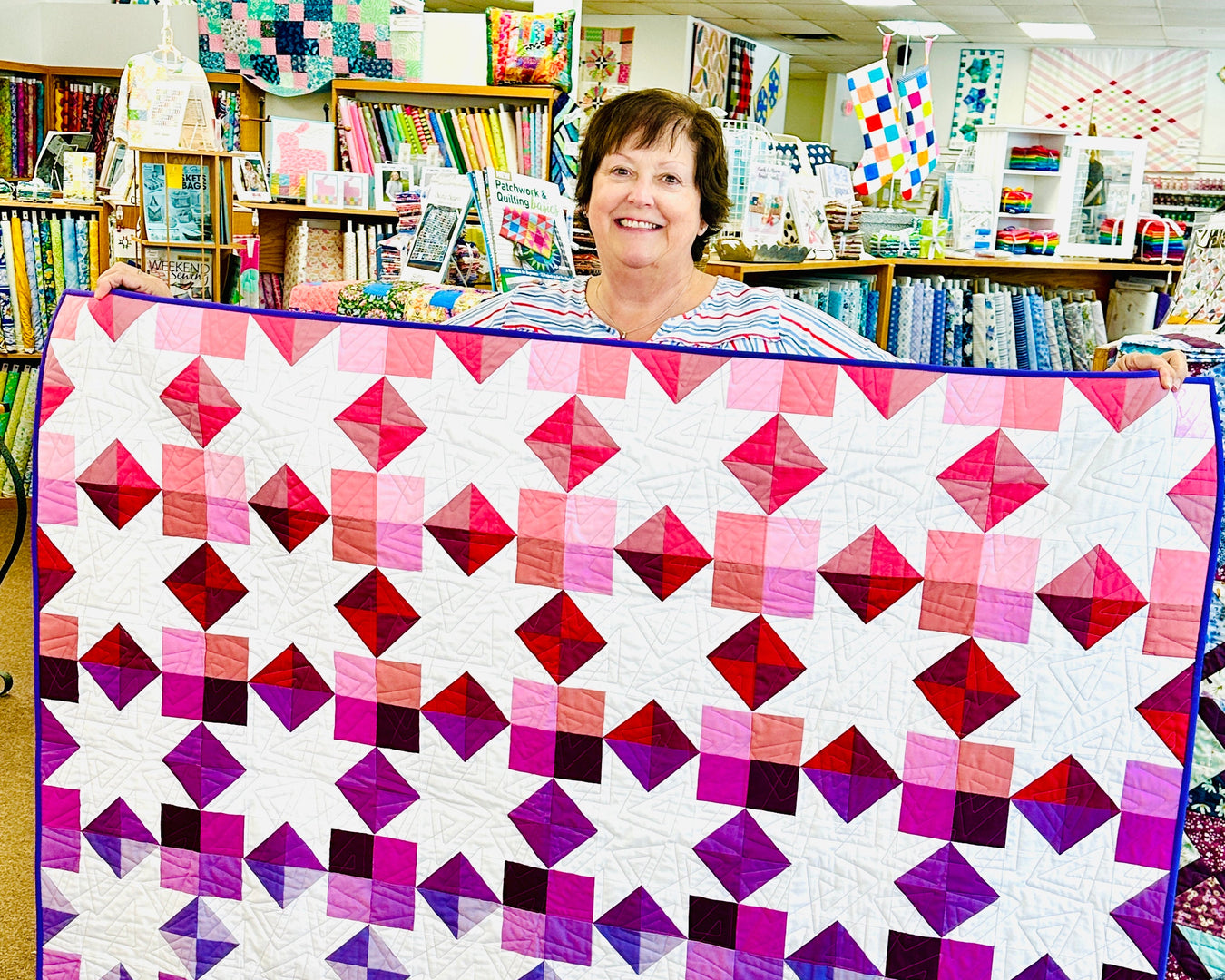 Person holding a colorful geometric quilt in a store setting