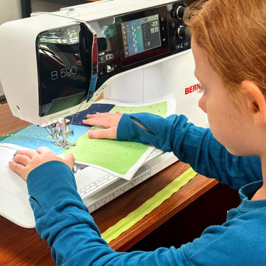 Person using a sewing machine on a wooden table