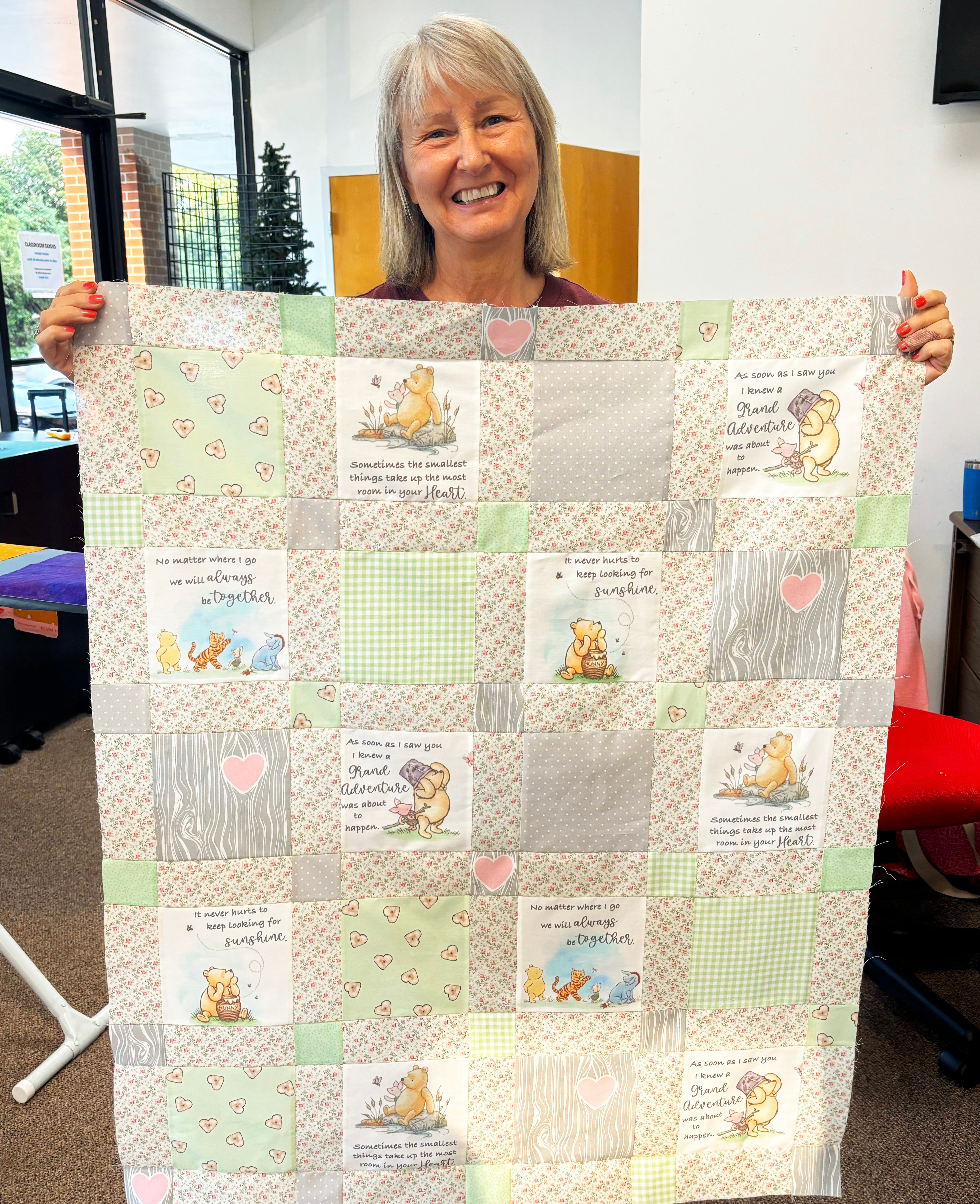 Person holding a patchwork quilt with cartoon characters and text