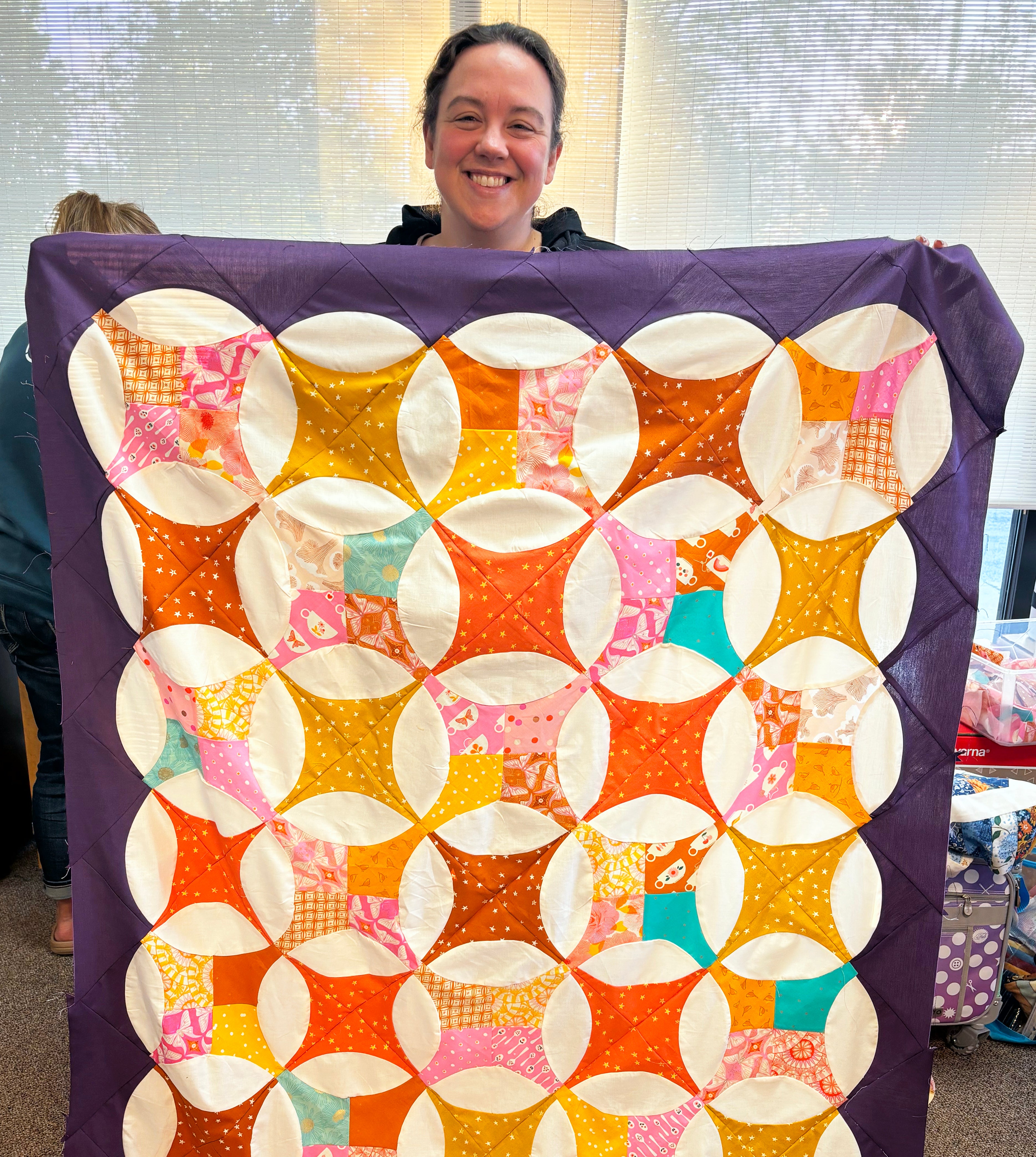 Person holding a colorful quilt with a geometric pattern