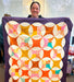 Person holding a colorful quilt with a geometric pattern