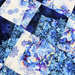 A close-up of a patchwork quilt featuring various blue and white fabrics with floral, marbled, and scroll patterns.