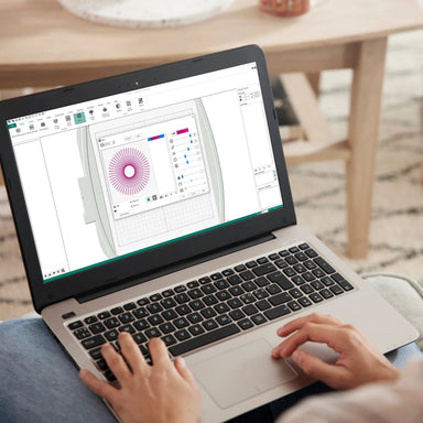 Person using a laptop with a design software on the screen in a home setting.