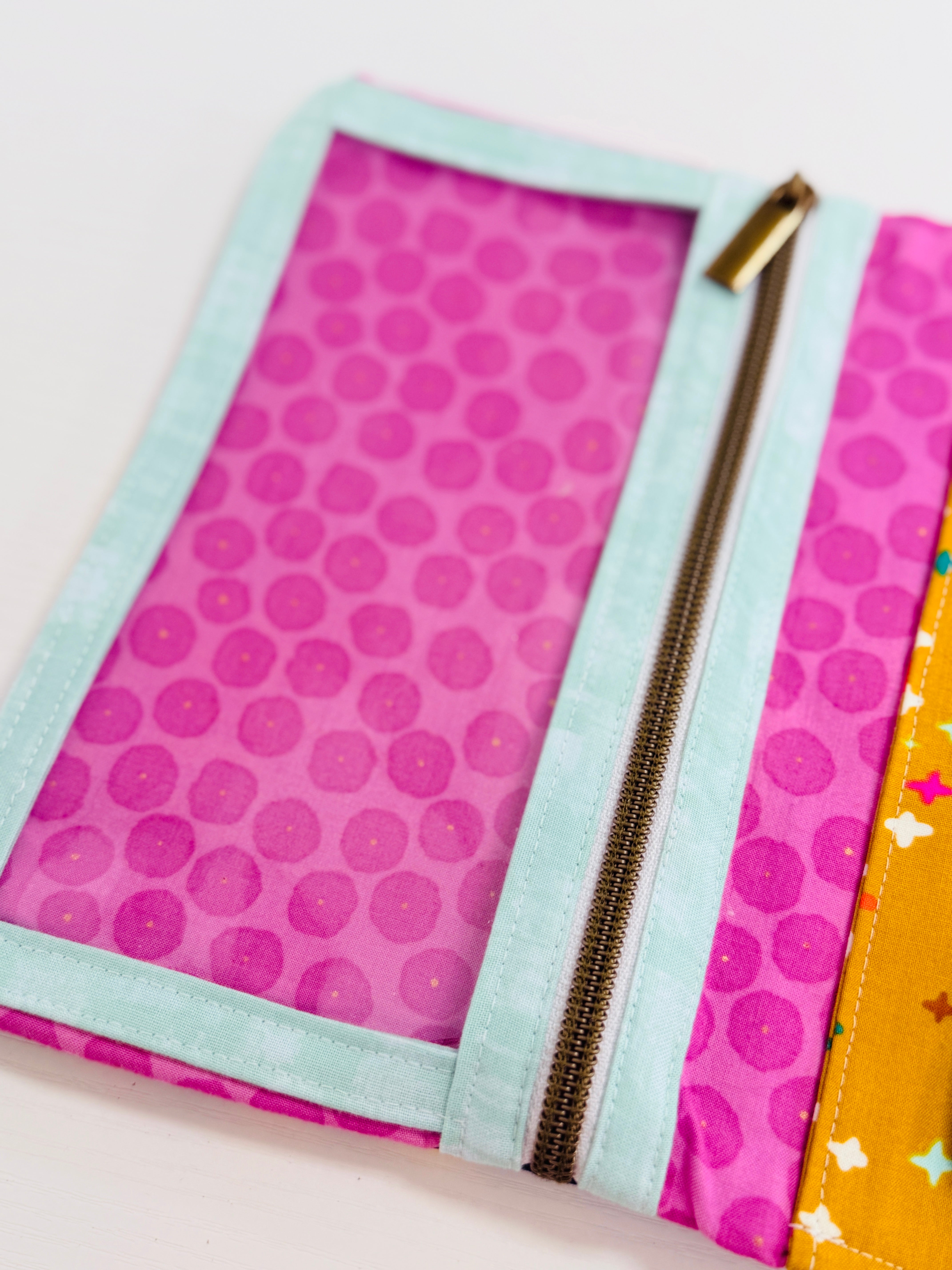 Pink polka dot pouch with a gold zipper on a white background