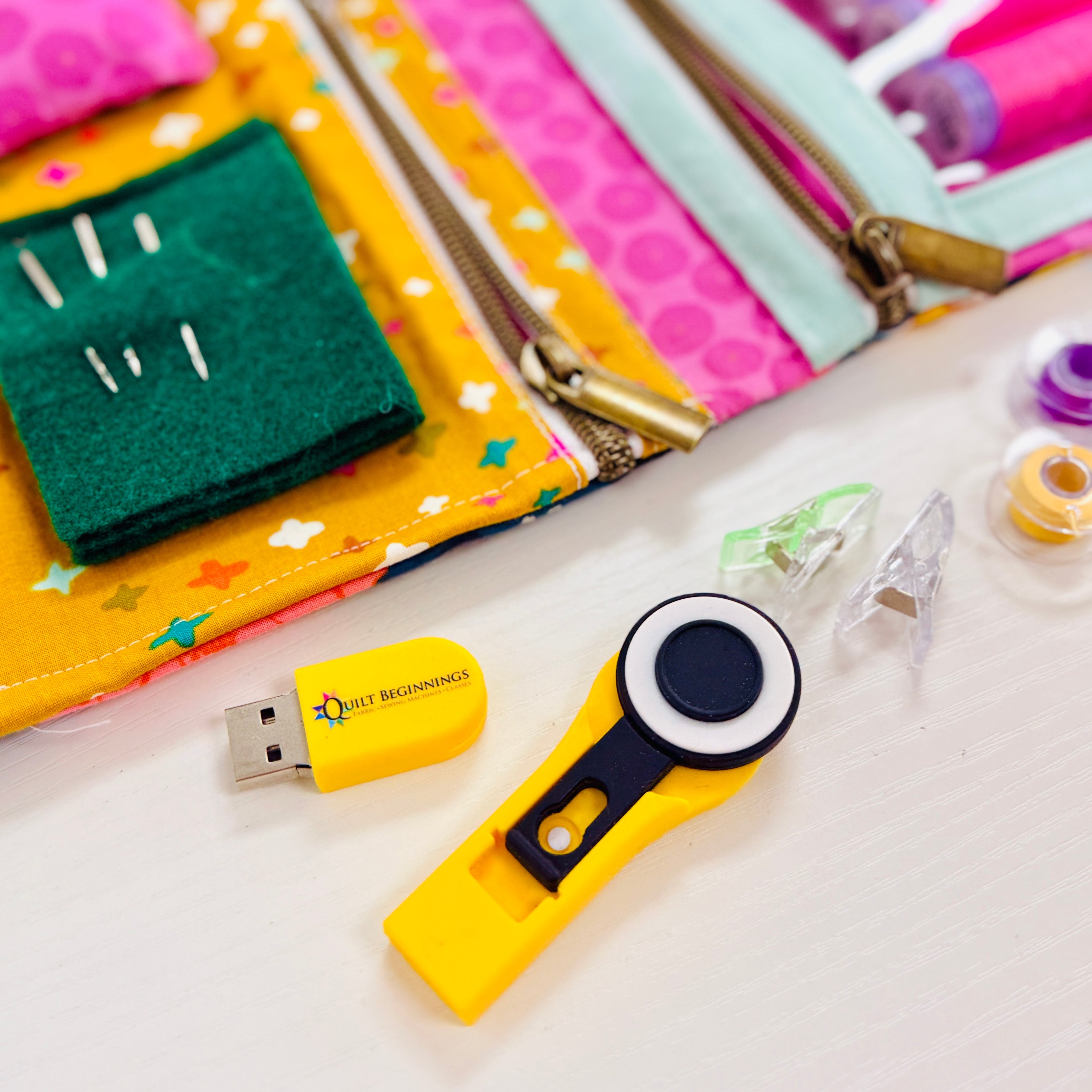 Collection of sewing tools and a USB drive on a colorful background