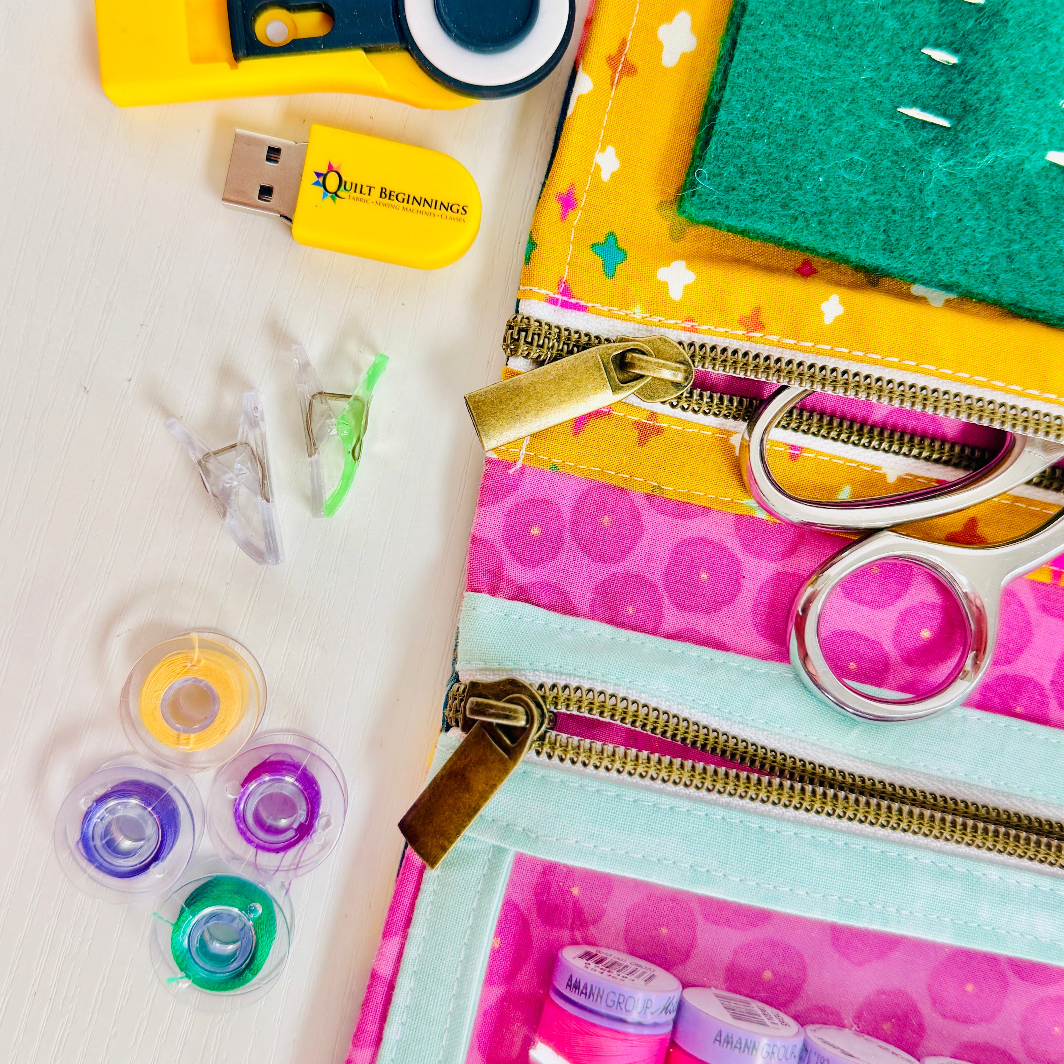 Collection of sewing and craft supplies including a USB drive, scissors, and thread on a white background.