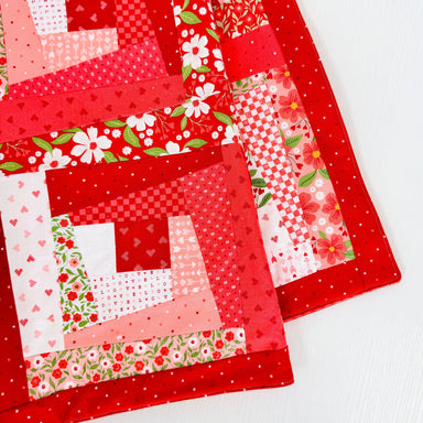 Red quilt block with floral patterns on a white background